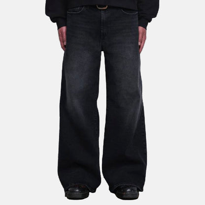 Person wearing black wide-leg jeans standing in front of a white shutter.